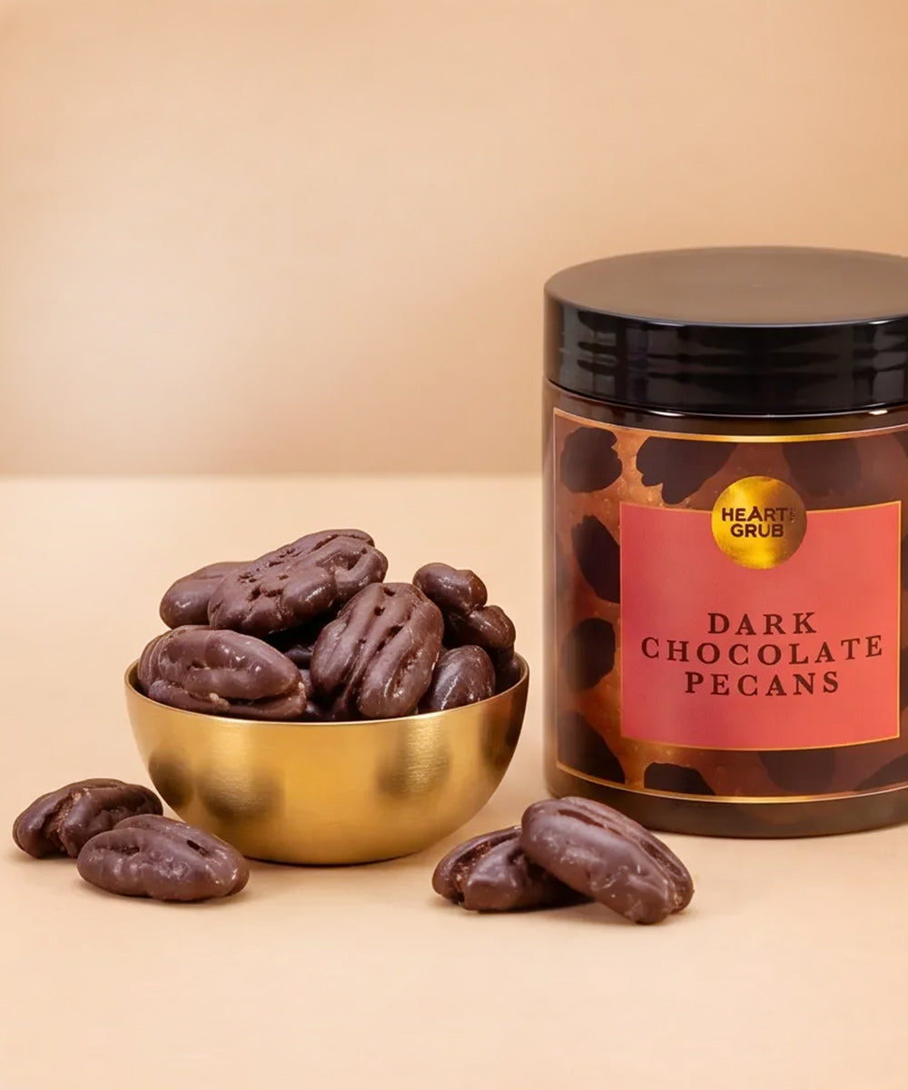 Dark Chocolate pEcans. Nuts. Chocolate Treats. Diwali gifts. Eid Gifts. Corporate Gifts. HeartiGrub. Abu Dhabi. Hearti Grub. Dark Chocolate Pecans candle in a clear glass jar with a black lid, featuring a brown and black leopard print pattern with a red label.
