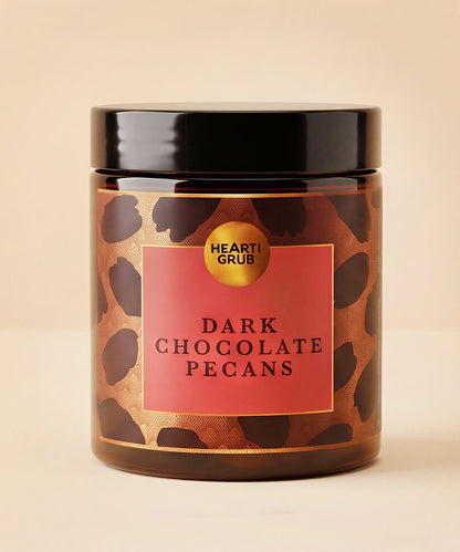Dark Chocolate pEcans. Nuts. Chocolate Treats. Diwali gifts. Eid Gifts. Corporate Gifts. HeartiGrub. Abu Dhabi. Hearti Grub. Dark Chocolate Pecans candle in a clear glass jar with a black lid, featuring a brown and black leopard print pattern with a red label.
