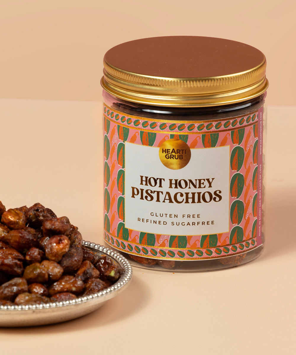 Jar of 'Hot Honey Pistachios' with a decorative label on a beige background. Bespoke Diwali gift. Thoughtful gifts. No Nasties. Clean Ingredients. UAE. Dubai. Abu Dhabi. Sharjah. Delivery throughout UAE. Nuts. Nut Butters. HeartiGrub
