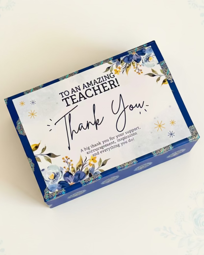 HeratiGrub Gift Hamper for Teachers Day. Delivery throughout the UAE. Gift box with 'Thank You' card for an amazing teacher on a textured surface.