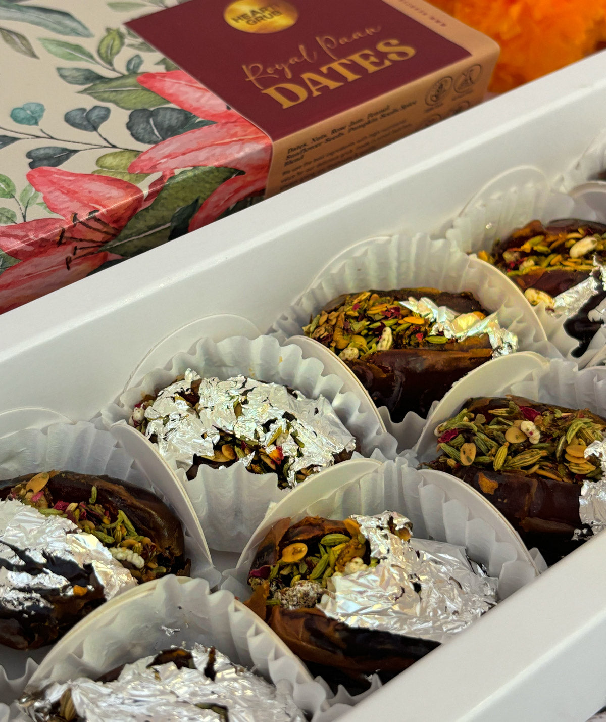 Jumbo Medjool. Royal Paan Khajur dates. No nasties. Gift set with Modak, Ganesh Chaturthi items, and a yellow ribbon on a wooden surface. Ganesh Chaturthi. Gifting. Made in Small Batches. Deliciously Decadent. Vegan Gluten Free Refined Sugar Free. Delicious Modak. Nuts. Delivery throughout U.A.E.