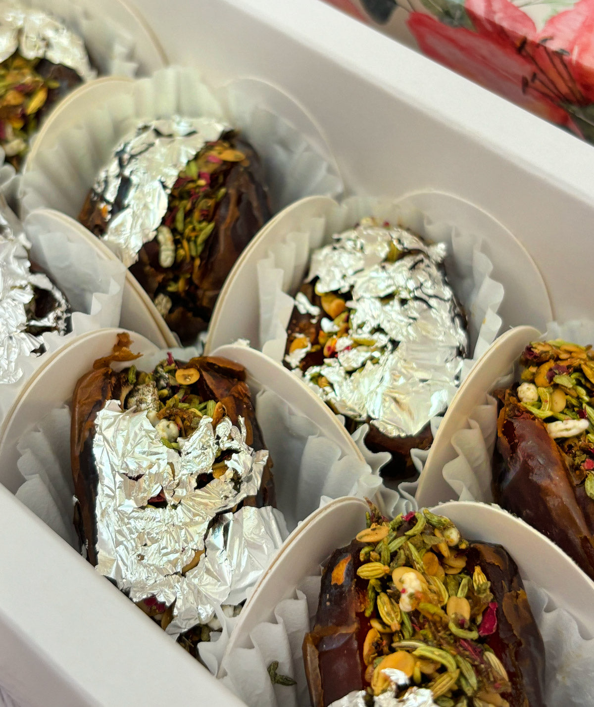 Jumbo Medjool. Royal Paan Khajur dates. No nasties. Gift set with Modak, Ganesh Chaturthi items, and a yellow ribbon on a wooden surface. Ganesh Chaturthi. Gifting. Made in Small Batches. Deliciously Decadent. Vegan Gluten Free Refined Sugar Free. Delicious Modak. Nuts. Delivery throughout U.A.E.