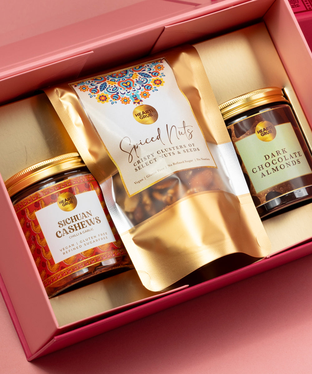Sichuan Cashew, Spiced Nuts, Dark Chocolate Almonds. Hearti Grub Pink gift box with containing nuts on a pink background. Bespoke Diwali gift. Thoughtful gifts. No Nasties. Clean Ingredients. UAE. Dubai. Abu Dhabi. Sharjah. Delivery throughout UAE. Nuts. Nut Butters
